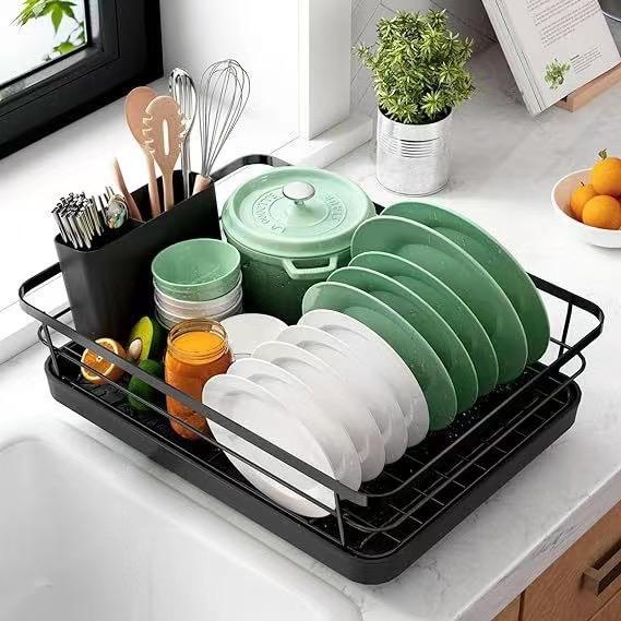 Dish drying rack with green and white dishes on a kitchen counter.